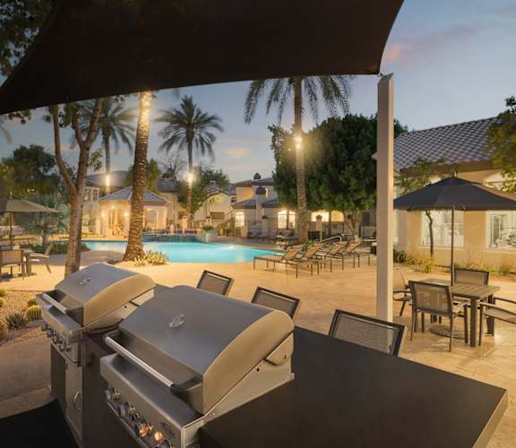 a backyard with a grill and a swimming pool at night