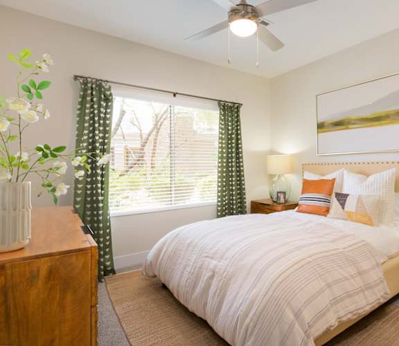 A bedroom with a bed, nightstand, and a painting on the wall.