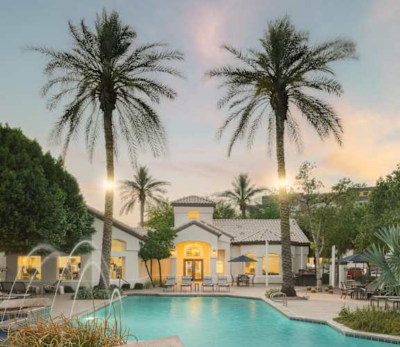 a swimming pool with palm trees in front of a hotel