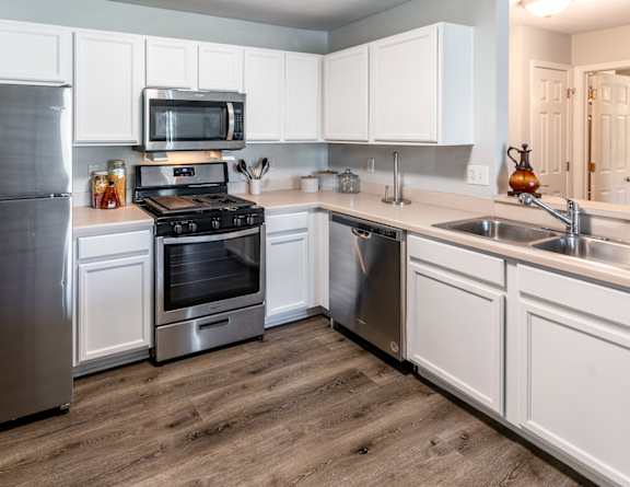 A modern kitchen with a stainless steel refrigerator, microwave, oven, and sink.