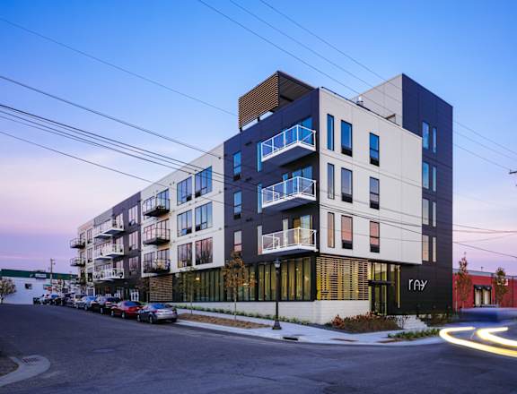a rendering of a building on a street corner with cars parked on the side of the road