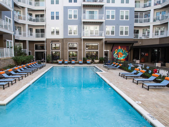 a swimming pool with lounge chairs in front of an apartment building at Lyric at Norton Commons Apartments, Prospect, Kentucky