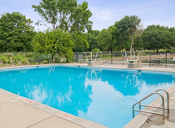 A pool surrounded by trees and a fence.
