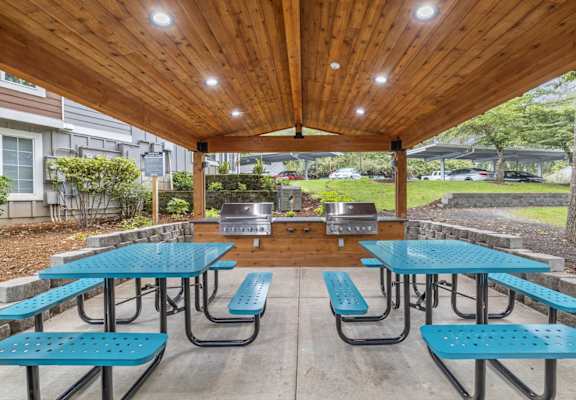 a covered patio with tables and chairs and a grill