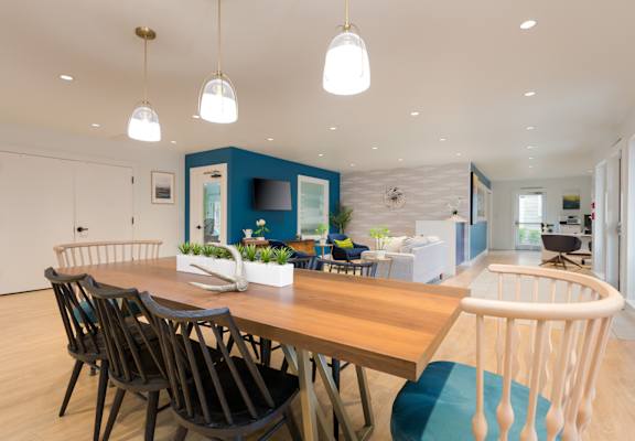 a dining room with a wooden table and chairs and a blue accent wall in the background