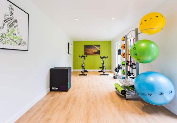 a home gym with weights and other exercise equipment in a white room with a green accent wall