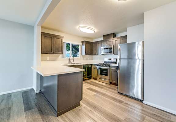 A kitchen with a refrigerator, oven, and microwave.