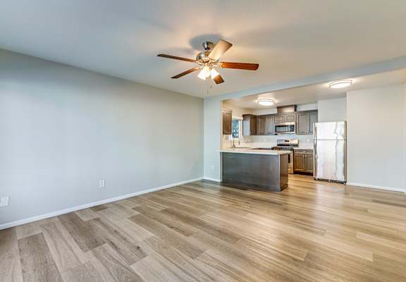 A room with a ceiling fan and wooden flooring.