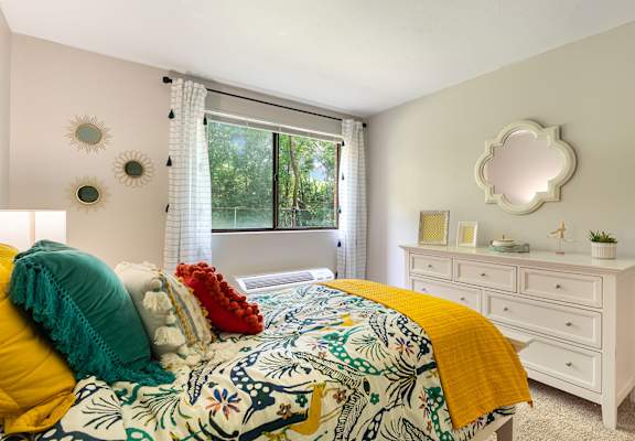 A bedroom with a floral bedspread and a white dresser.
