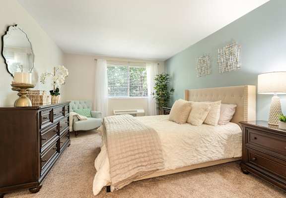 A bedroom with a bed, nightstand, and dresser.