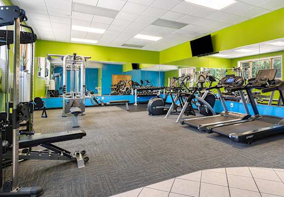 A gym with a variety of equipment including treadmills, weights, and exercise machines.