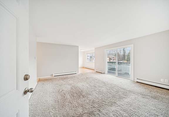 A room with a carpeted floor and a door on the left side.