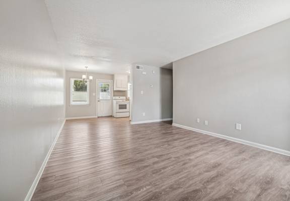 A spacious room with wood flooring and a white refrigerator.