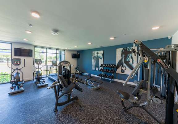 a gym with weights and cardio equipment in a building with windows