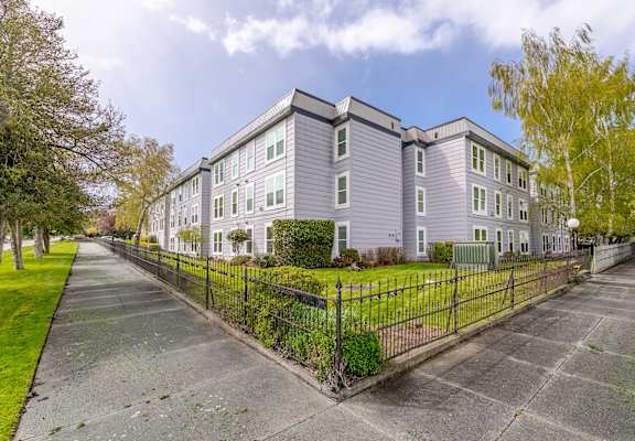A grey apartment building with a black fence in front.