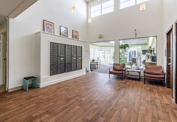 A room with wooden floors and a white wall with a black calendar on it.