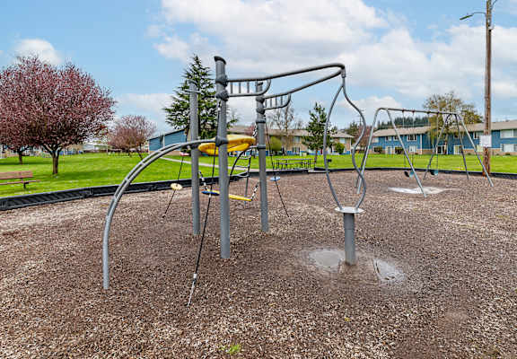 A playground with a swing set and a tree in the background.