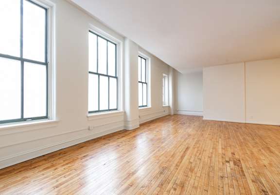 an empty living room with hardwood floors and large windows at 26 West, Managed by Buckingham Urban Living, 26 West Washington Street, IN
