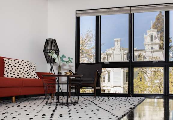 a living room with a red couch and a black and white rug