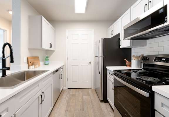 a kitchen with white cabinets and black appliances