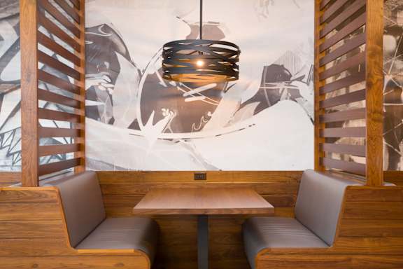 A wooden booth with a table and two grey chairs.