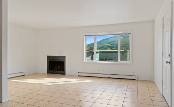 a living room with a fireplace and a large window  at ReNew Eagle River, Alaska, 99577