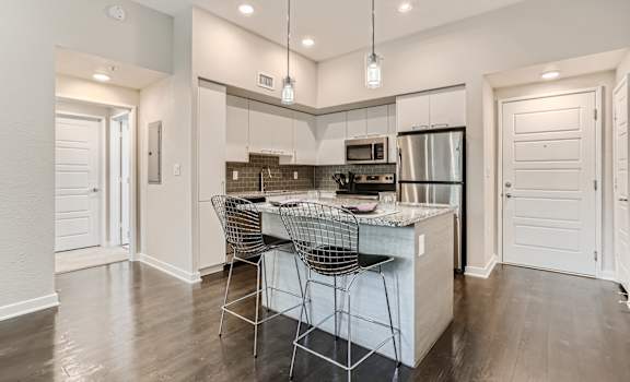 a kitchen with white cabinetry and a large island with a marble countertop