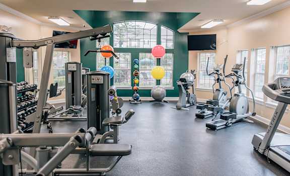 a gym with cardio machines and weights and a window