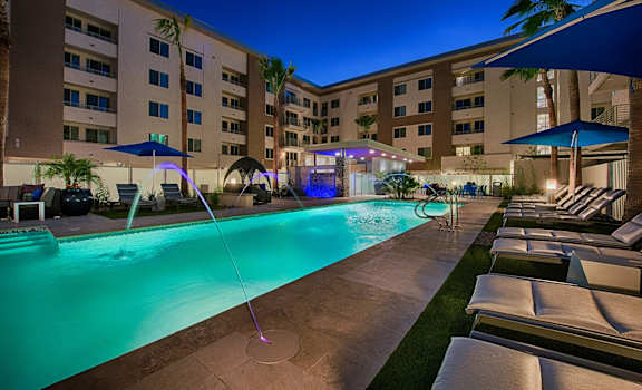 a large swimming pool with lounge chairs and umbrellas in front of a hotel at The View at Cascade Apartments, Scottsdale, Arizona
