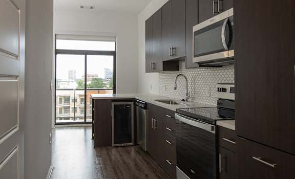 A kitchen with dark wood cabinets and a black dishwasher.