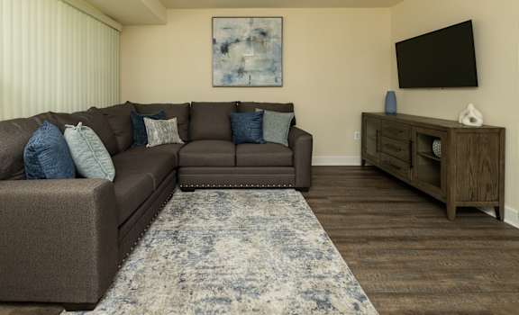 A living room with a brown couch, a rug, and a wooden cabinet.