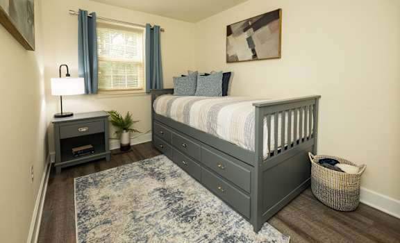 A bedroom with a bed, nightstand, and window.