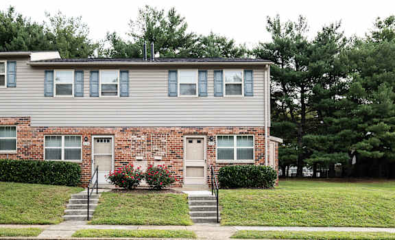 A two-story house with a brick facade and a grey siding.
