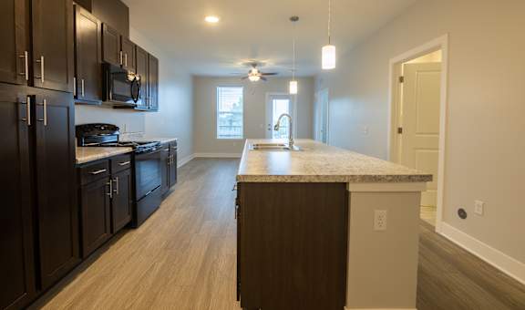 A kitchen with dark brown cabinets and a light brown island.