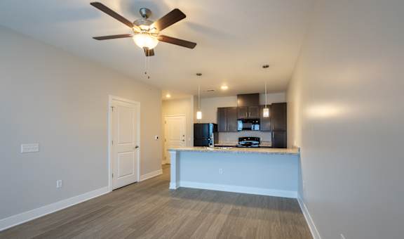 A room with a ceiling fan and a kitchen island.