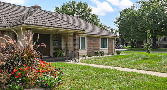 A house with a brown roof and a small front yard with a flower bed.