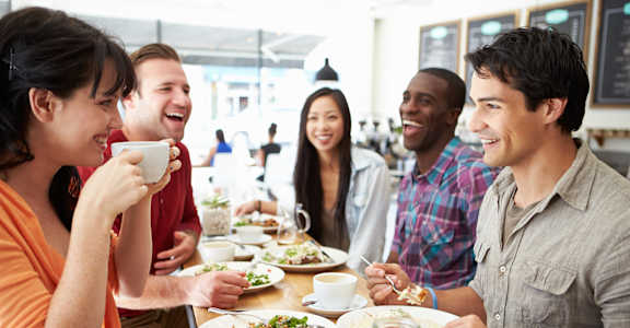 A group of people are sitting around a table eating food.