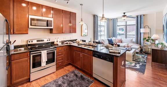 a kitchen with wooden cabinets and a living room with a couch at Park and Kingston, Charlotte, North Carolina