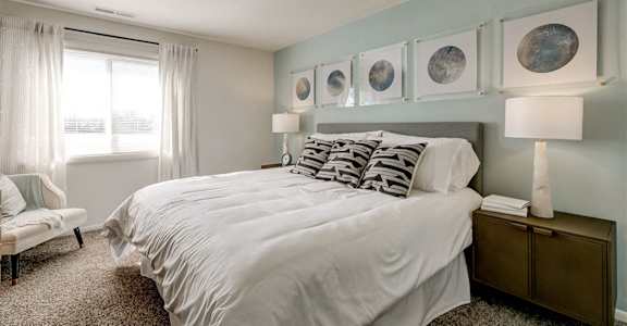 a bedroom with a white bed and some pictures on the wall at DonCaster Village Apartments, Parkville, MD, 21234