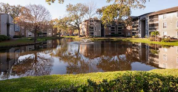 A serene lake surrounded by buildings and trees.