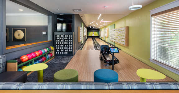 A bowling alley with a wooden lane and bowling balls on the side.