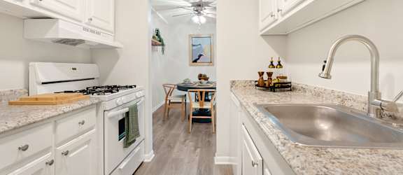 A kitchen with white cabinets and a marble countertop.