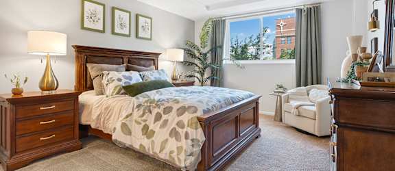 A bedroom with a large bed and a chair.