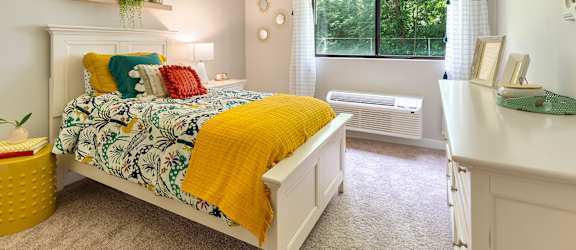 A bedroom with a bed, a window, and a yellow blanket.