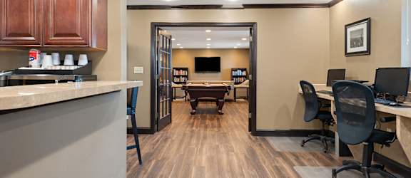 A modern office space with wood flooring and a kitchenette.