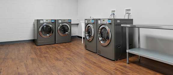 Three front load washing machines in a laundry room.