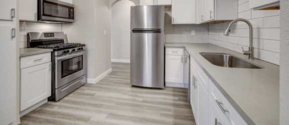 A kitchen with white cabinets and a stainless steel refrigerator.