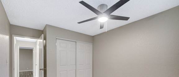 A room with a ceiling fan and a door.