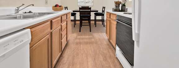A kitchen with wooden cabinets and a white fridge. at Winding Hills Apartments, Davenport, Iowa