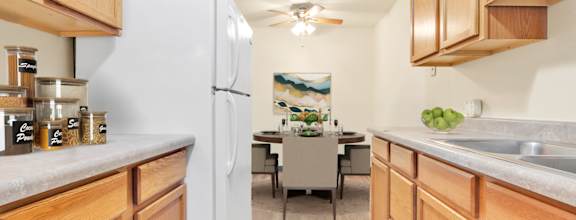 A kitchen with wooden cabinets and a white refrigerator. at Indian Ridge Apartments, Davenport, IA, 52807
